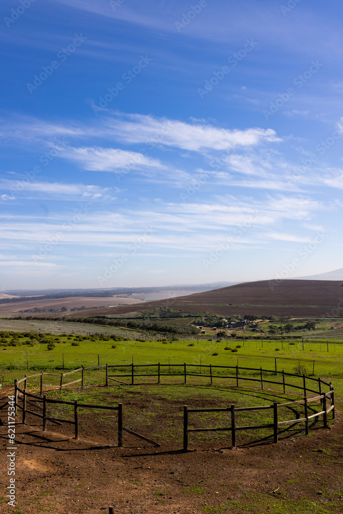 Vertical image of landscape of countryside and agricultural fields and round fence on sunny day