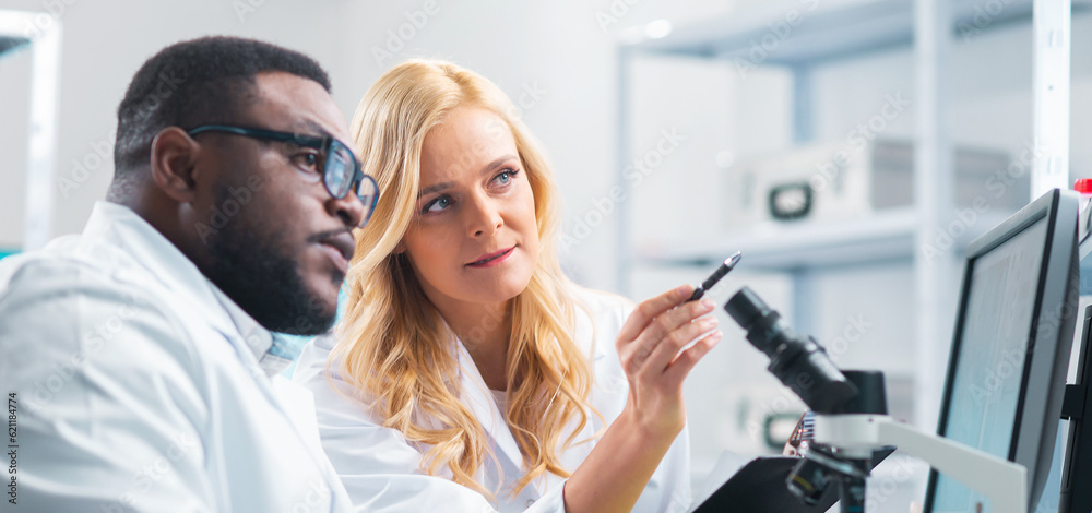 Medical scientists working in lab. Doctor teaching interns to make analyzing research. Laboratory tools: microscope, test tubes, equipment. Science and health care concept. Medical scientists working in lab. Doctor teaching interns to make analyzing research. Laboratory tools: microscope, test tubes, equipment. Science and health care concept.
