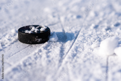 Photography hockey puck lies on the snow close-up