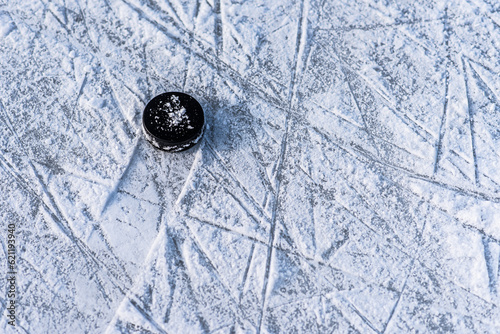 Photography hockey puck lies on the snow close-up