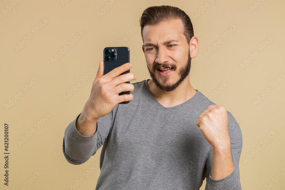 Happy excited joyful lebanese man in long sleeve use smartphone typing browsing shouting say wow yes found out great big win, good news, lottery goal achievemen, celebrating success, winning game Happy excited joyful lebanese man in long sleeve use smartphone typing browsing shouting say wow yes found out great big win, good news, lottery goal achievemen, celebrating success, winning game