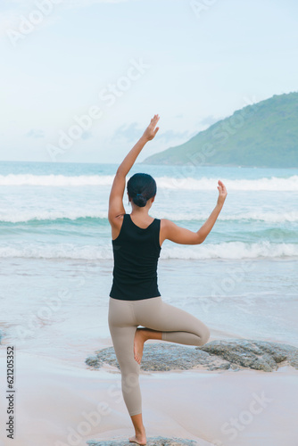 In a graceful yoga flow, a woman nurtures her body and mind on the beach, flowing with the natural rhythm of the tides and finding inner harmony.