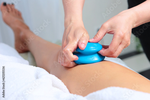 Massage with silicone jars on outside of thigh.Silicone jars for body skin massage.Massage remedy for getting rid of cellulite.Body massage in beauty salon.Concept of beauty industry.