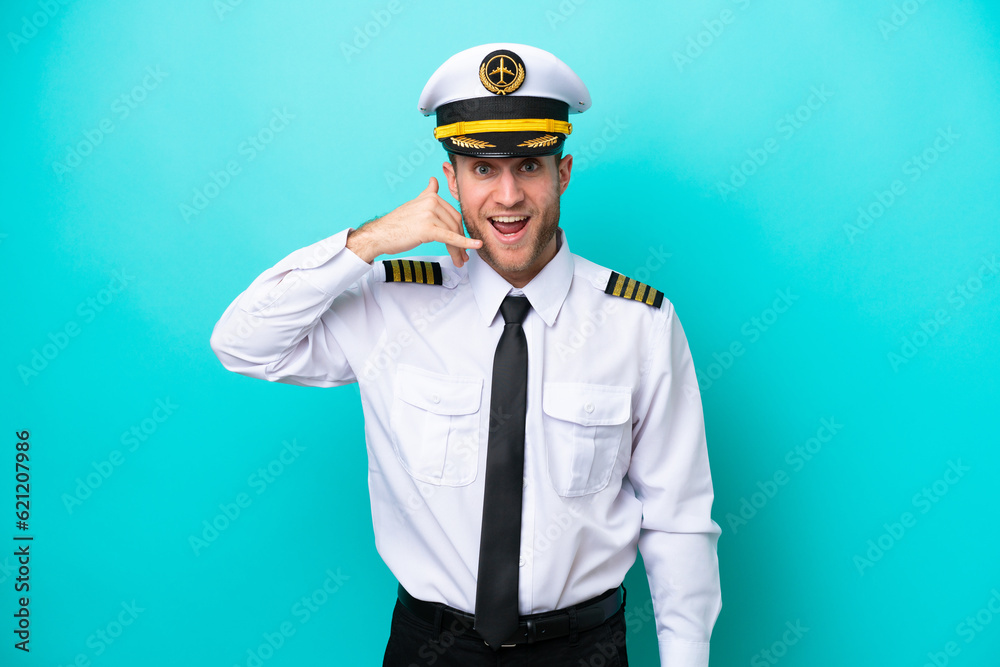 Airplane caucasian pilot isolated on blue background making phone gesture. Call me back sign