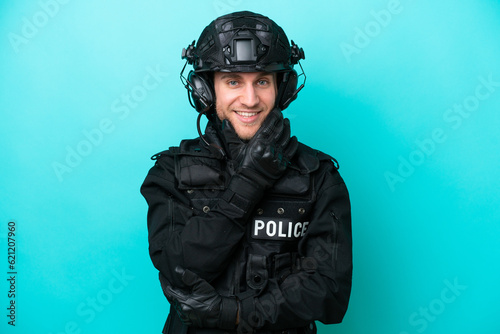 SWAT caucasian man isolated on blue background smiling © luismolinero