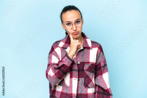 Young Arab woman isolated on blue background and thinking