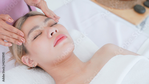 Woman having facial massage by masseuse.