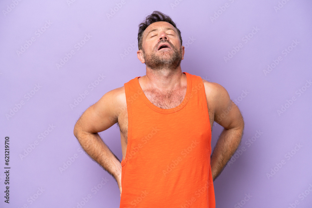 Middle age caucasian man isolated on purple background suffering from backache for having made an effort