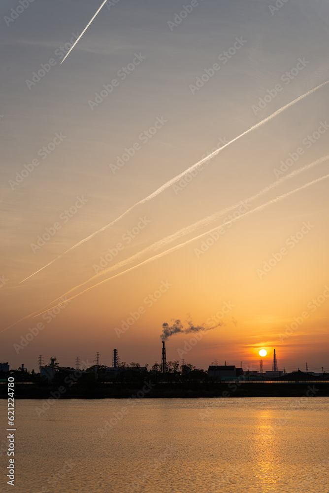 工場群に沈む夕日と飛行機雲