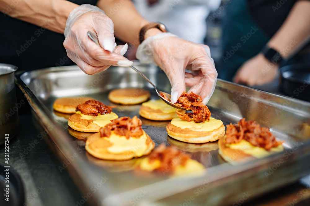 woman chef hand cooking pancakes with meat, bacon and cheese sauce