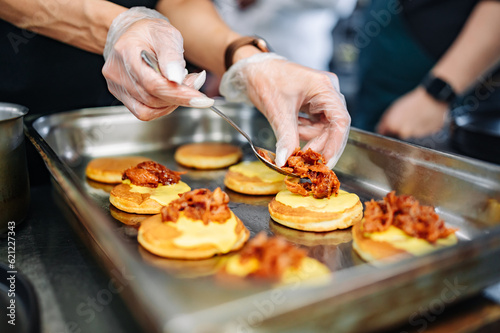 woman chef hand cooking pancakes with meat, bacon and cheese sauce