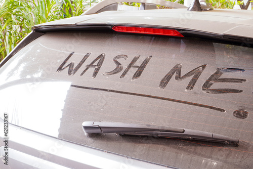 dirty car rear widescreen covered with dust with wording WASH ME , car wash and car care concept , selective focus photo