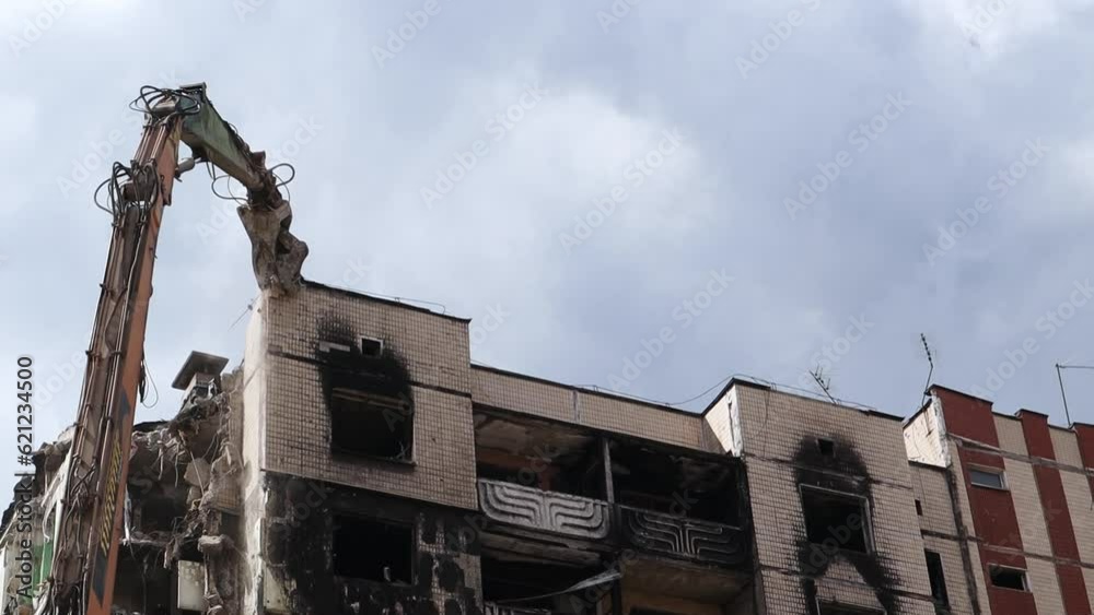 Facade of a residential abandoned multi-storey building after a strong fire. A construction excavator with a hydraulic crusher demolishes a house for repairs. The collapse of a residential building. Facade of a residential abandoned multi-storey building after a strong fire. A construction excavator with a hydraulic crusher demolishes a house for repairs. The collapse of a residential building.