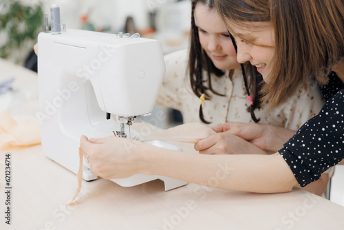 Smiling small girl dressmaker, by step sewing master class in school photo