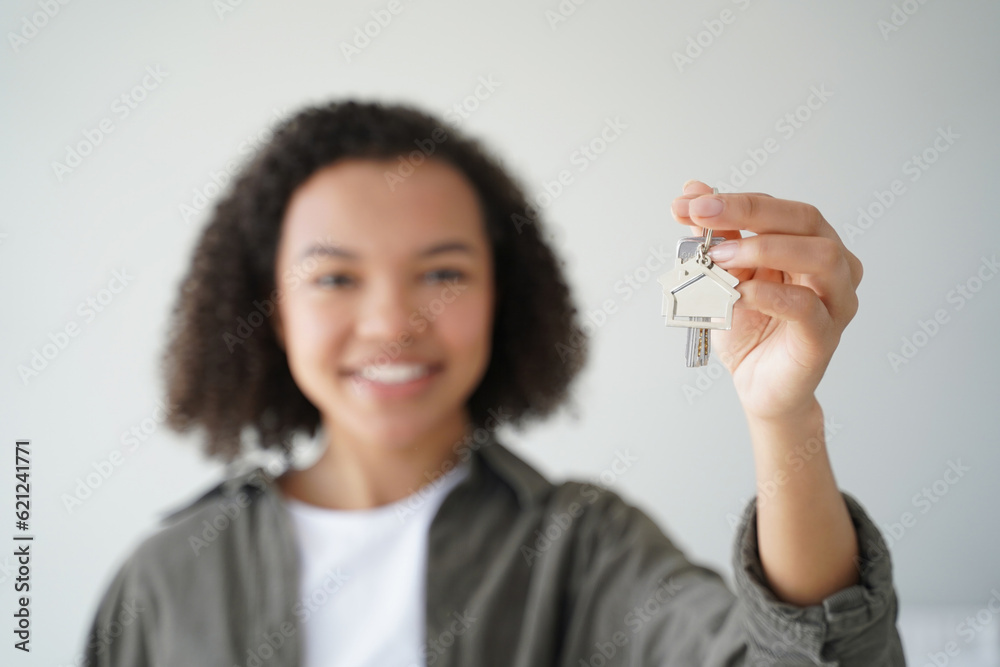 Happy biracial teen homeowner shows new home keys. Smiling lady holds apartment key, focus on hand. Mortgage ad. Happy biracial teen homeowner shows new home keys. Smiling lady holds apartment key, focus on hand. Mortgage ad.