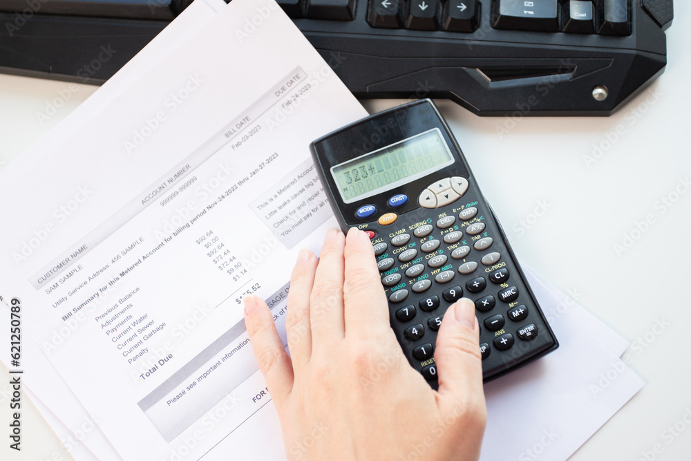 a woman at her desk counts the cost of utility bills, rising prices for water and heating a woman at her desk counts the cost of utility bills, rising prices for water and heating