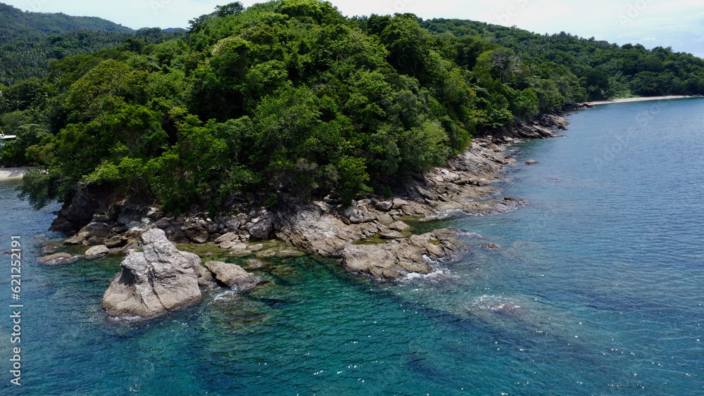 View of the sea and hiils. Aerial view of tropical island and stone cape. Blue sea, rocky shore and jungle.