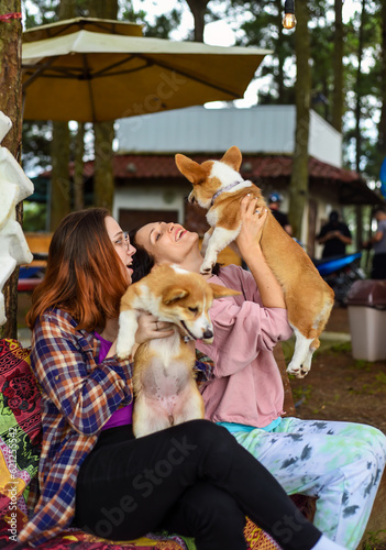 Canvas Print mother with her daughter hugging their corgi dogs in the garden