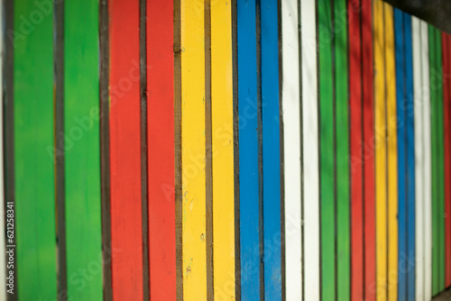 Colored fence. Beautiful fence. Different color on boards. Painted material.