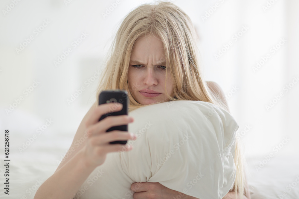 Frustrated Woman on Bed Using Mobile Phone with Angry Expression. Frustrated Woman on Bed Using Mobile Phone with Angry Expression.