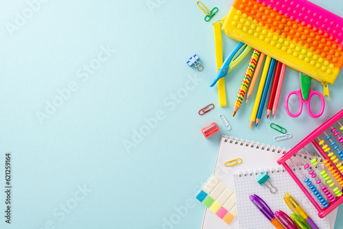 Dive into the joy of learning with this creative top-down snapshot: an array of colorful school supplies beautifully displayed on a pastel blue surface, offering copyspace for text or adverts
