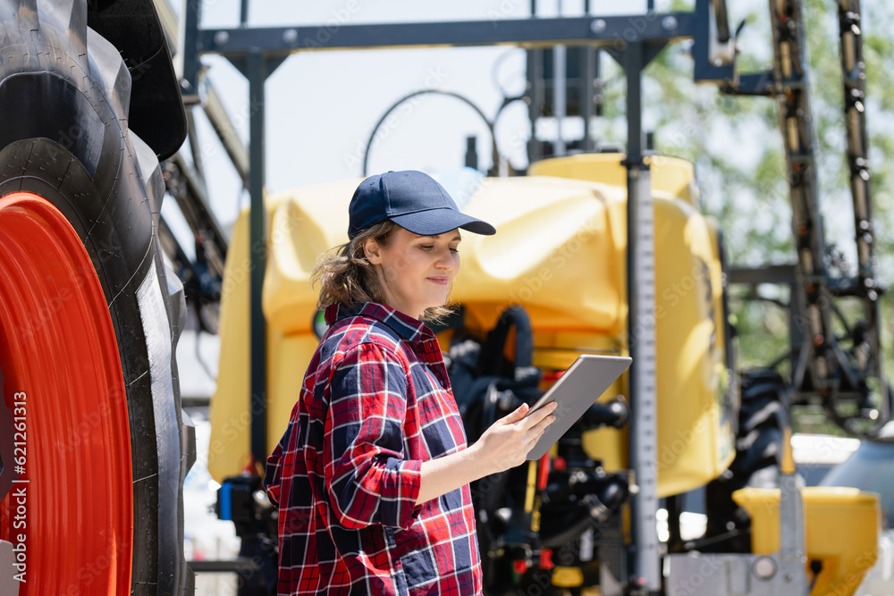 Woman farmer with a digital tablet on the background of an agricultural tractors Woman farmer with a digital tablet on the background of an agricultural tractors