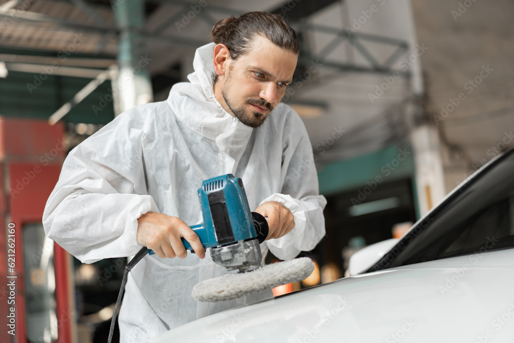 Caucasian man holds a polisher in the hand and polishes the car at car service Caucasian man holds a polisher in the hand and polishes the car at car service