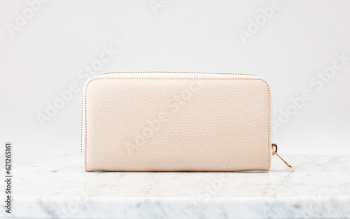 Luxury women 's handbag, wallet. Luxury beige leather handbag on white background, on marble floor. The camera is right in front of wallet. Fashionable trendy accessory