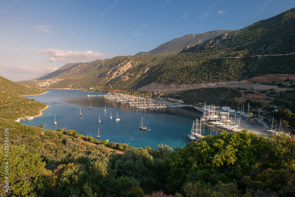 Panoramic landscape of a lagoon and marina full of sail boats between forested mountains, Kas, Turkey