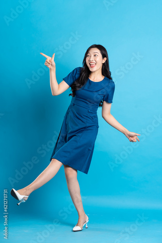 Portrait of beautiful woman in blue dress, isolated on blue background