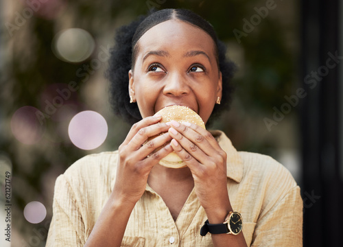 Thinking, fast food and black woman biting a burger in an outdoor restaurant as a lunch meal craving deal. Breakfast, sandwich and young female person or customer enjoying a tasty unhealthy snack