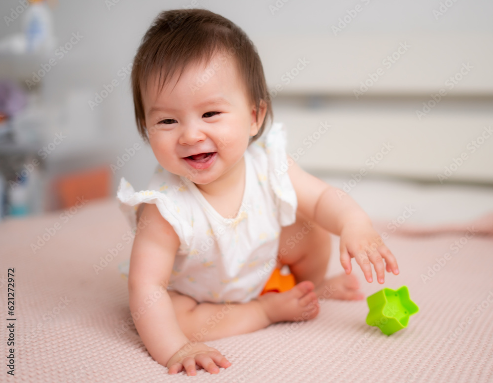 lifestyle home portrait of 9 months old mixed ethnicity Asian Caucasian baby girl playing happy and carefree on bed crawling and handling color blocks in childhood and nursery concept lifestyle home portrait of 9 months old mixed ethnicity Asian Caucasian baby girl playing happy and carefree on bed crawling and handling color blocks in childhood and nursery concept