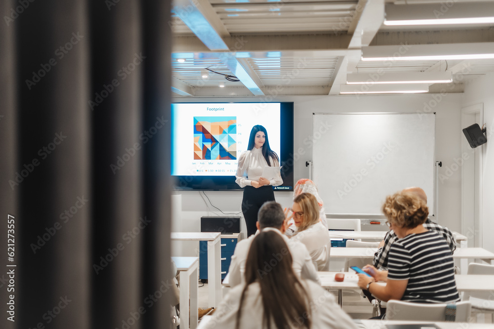 Presenting analytical report at modern conference room. Multicultural group of businesspeople listening to a successful businesswoman giving a speech Presenting analytical report at modern conference room. Multicultural group of businesspeople listening to a successful businesswoman giving a speech