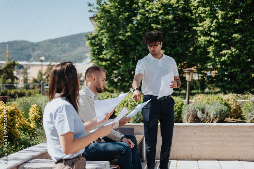Young business people planning, doing paperwork, discussing reports while working out in the city on a sunny day. Remote work concept Young business people planning, doing paperwork, discussing reports while working out in the city on a sunny day. Remote work concept