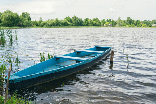 A wooden boat on the shore of the lake. Old boat for swimming. A wooden boat for fishing on the lake © Рома Пляшко