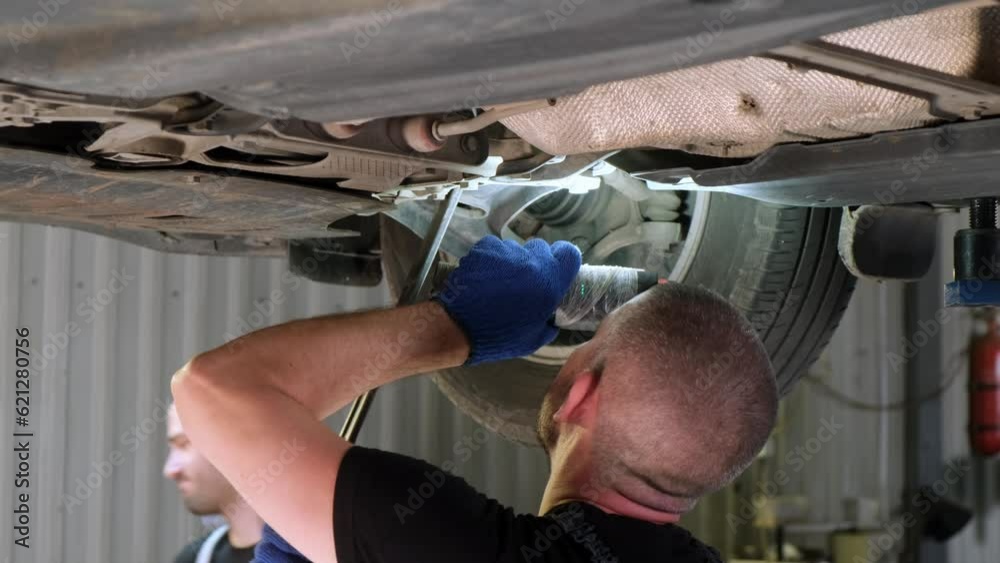 Auto mechanic working underneath car lifting machine at the garage. Auto repair shop, Car service, repair.
Auto mechanic working underneath car lifting machine at the garage. Auto repair shop, Car service, repair.
