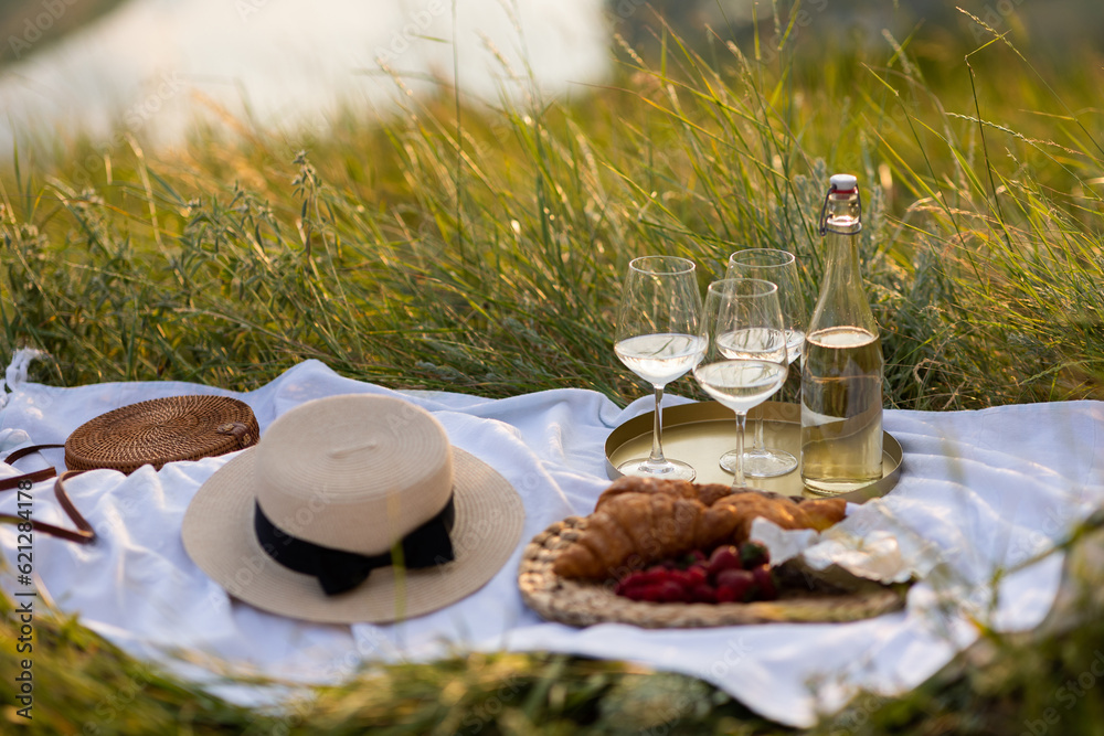 Romantic picnic with croissants, white wine and fresh berries in the mountain at sunny summer day.