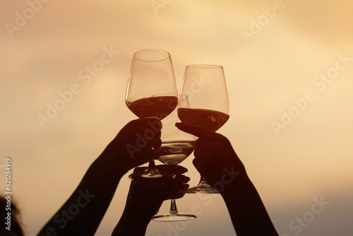 Obraz na płótnie Friends clinking glasses with wine and enjoying wine against a beautiful sunset. w salonie