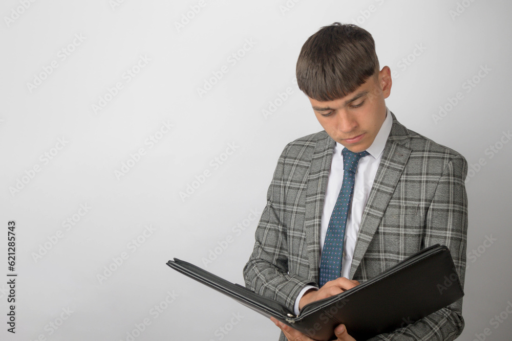 Young entrepreneur wearing a suit and tie writing in a folder Young entrepreneur wearing a suit and tie writing in a folder
