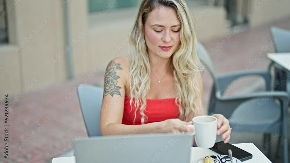 Young blonde woman drinking coffee using laptop at coffee shop terrace Young blonde woman drinking coffee using laptop at coffee shop terrace