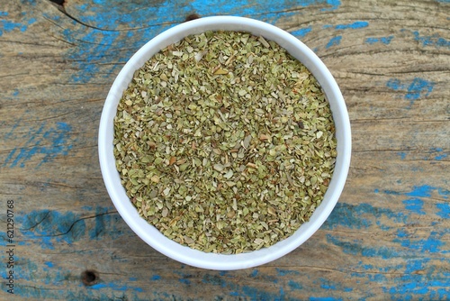 Dried oregano spice in a bowl on old wooden background top view 