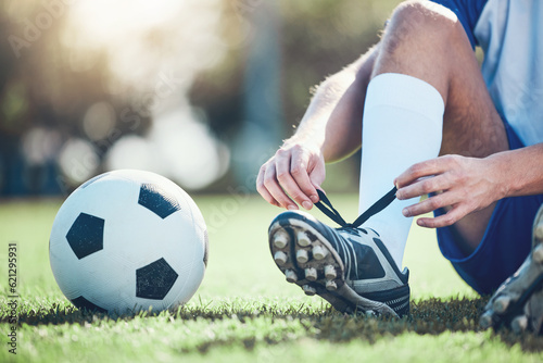 Ball, man and soccer player tie shoes for training, fitness games and performance on field. Closeup, football athlete and lace sneakers on feet, grass pitch and sports competition on stadium ground