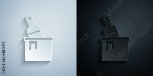 Paper cut Paint bucket with brush icon isolated on grey and black background. Paper art style. Vector