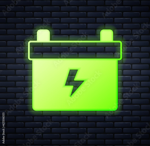 Glowing neon Car battery icon isolated on brick wall background. Accumulator battery energy power and electricity accumulator battery. Vector