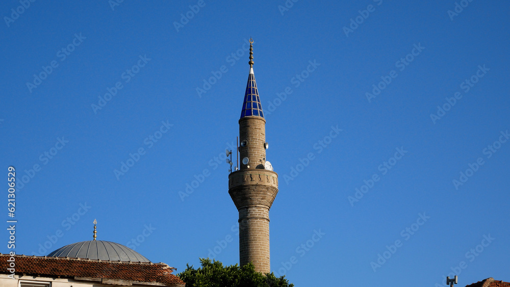 Obraz premium The building of a Muslim mosque with a blue tower against a blue sky. Prayer house for Muslims and adherents of Islam