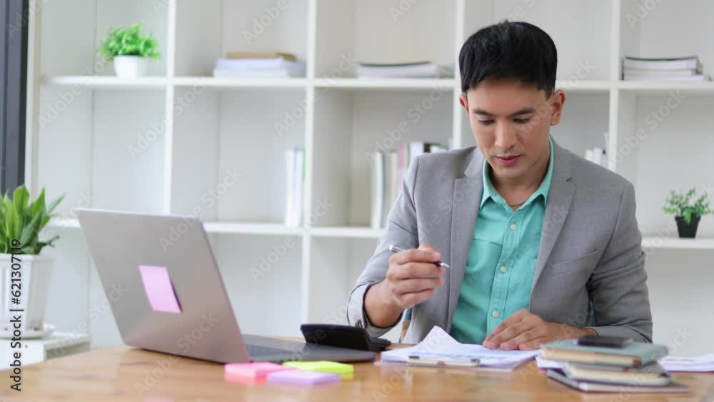Serious businessman working on paperwork on laptop and financial accounting documents with calculator on office desk. Serious businessman working on paperwork on laptop and financial accounting documents with calculator on office desk.