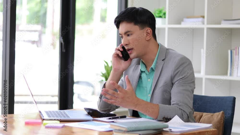 Serious businessman working on documents on laptop while talking with someone on the phone. Serious businessman working on documents on laptop while talking with someone on the phone.