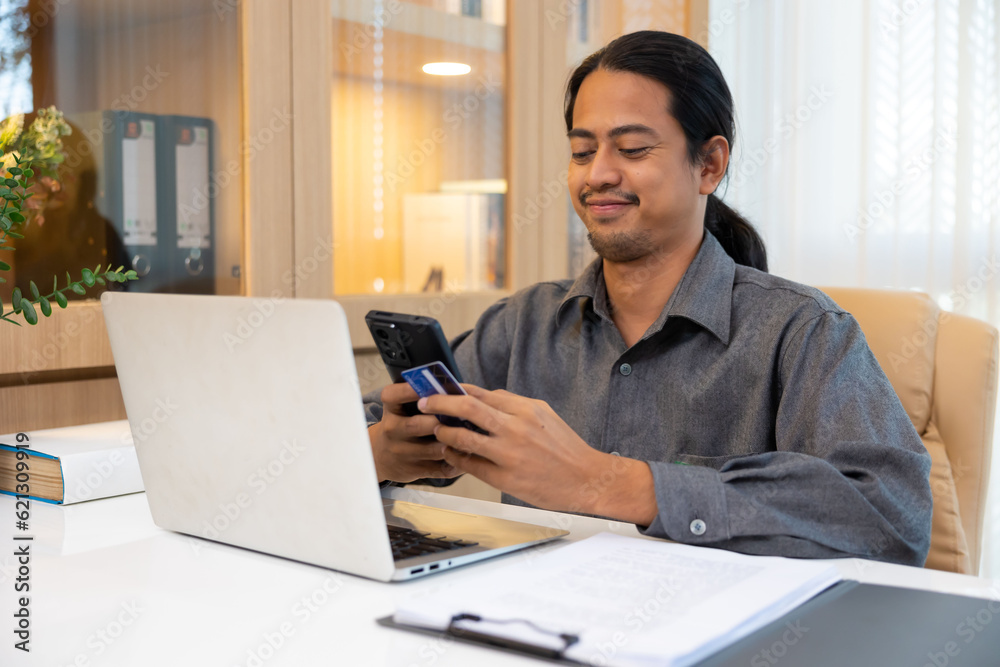 Asian hipster man hands holding credit card and using smartphone for payment. Online shopping Asian hipster man hands holding credit card and using smartphone for payment. Online shopping