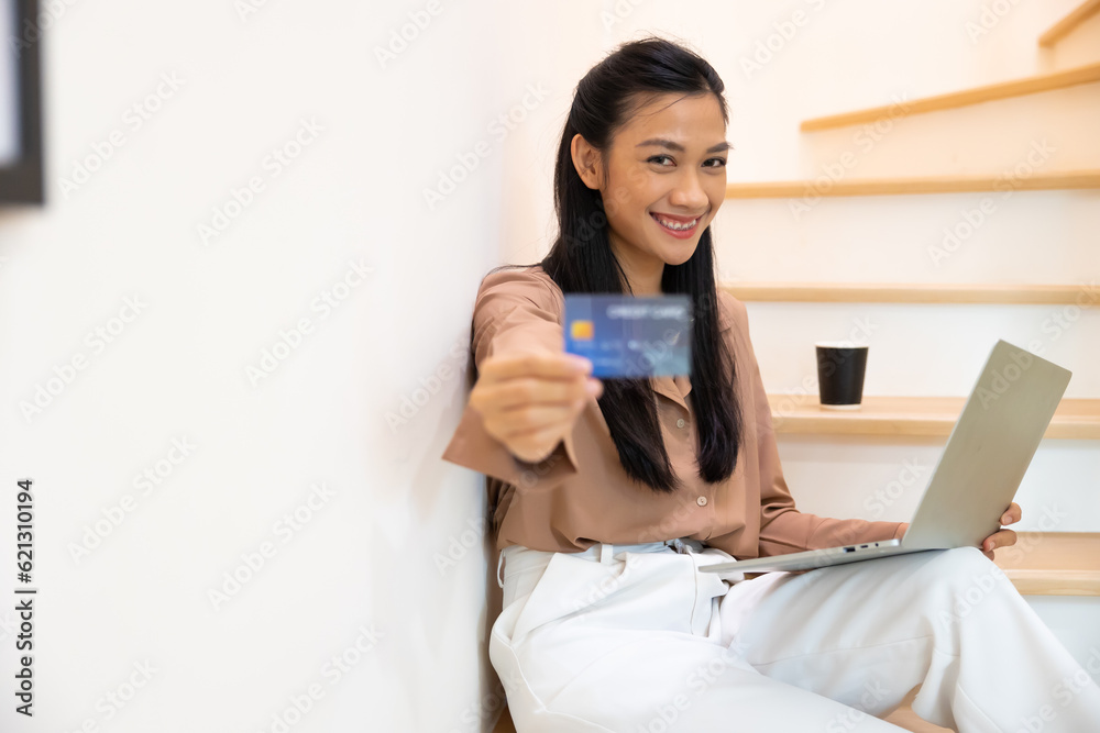 Female show credit card mockup in her hand. Young Asian female hands holding credit card and using laptop computer for payment. Online shopping Female show credit card mockup in her hand. Young Asian female hands holding credit card and using laptop computer for payment. Online shopping