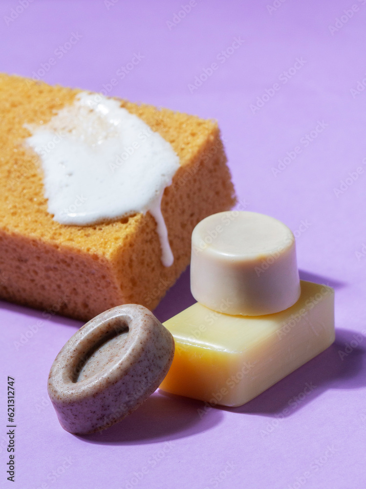 Handmade soap with the addition of coffee and wild herbs and a sponge with foam on a purple background.